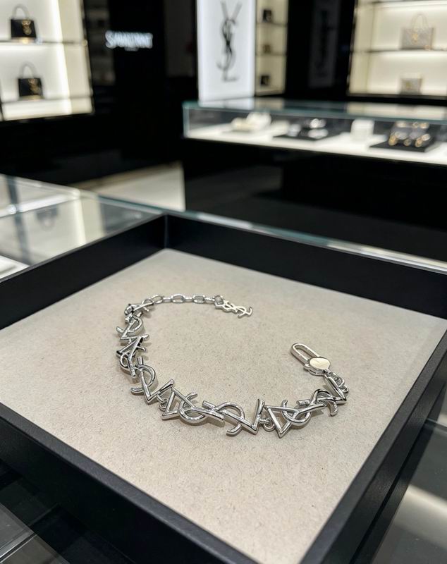 Silver monogram chain bracelet with interlocking letter charms displayed on a velvet tray